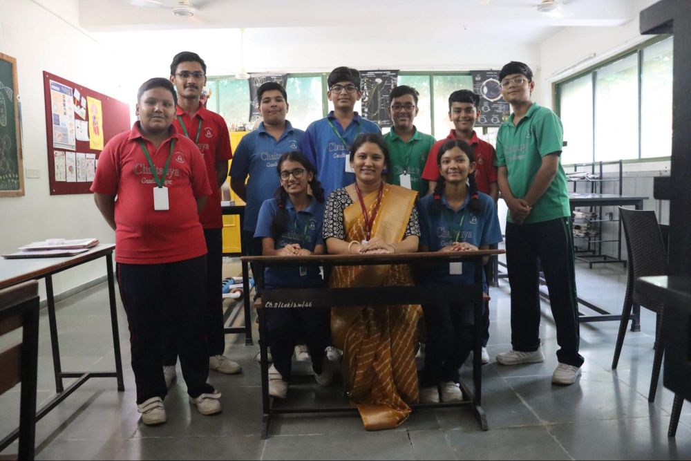 Teacher with students posing in a classroom at Chaitanya School, the Best CBSE School in Gandhinagar.