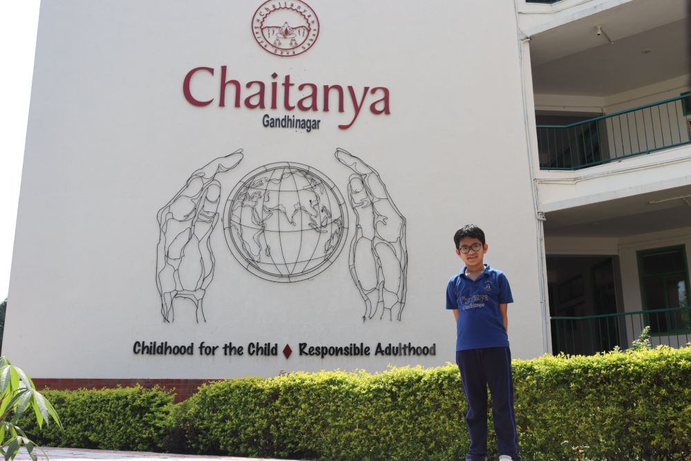 Child posing in front of Chaitanya School Gandhinagar building – CBSE Schools Near Me